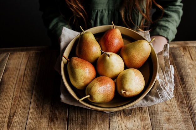 Op een houten tafel een bord met verse oogst van peren