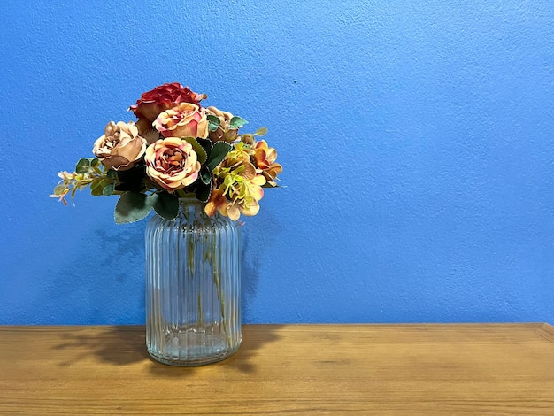 Op een houten tafel staat een vaas met bloemen.