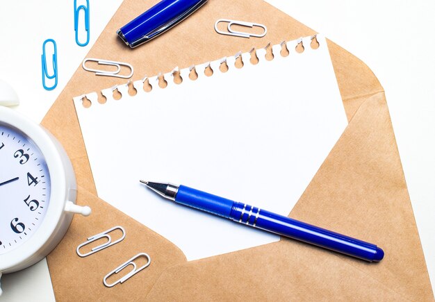 Op een lichte ondergrond een open envelop, een witte wekker, witte en blauwe paperclips, een blauwe pen en een vel papier met een plek om tekst in te voegen.