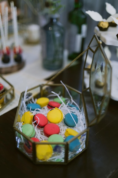 Op een tafel staat een glazen bak met kleurrijke snoepjes.