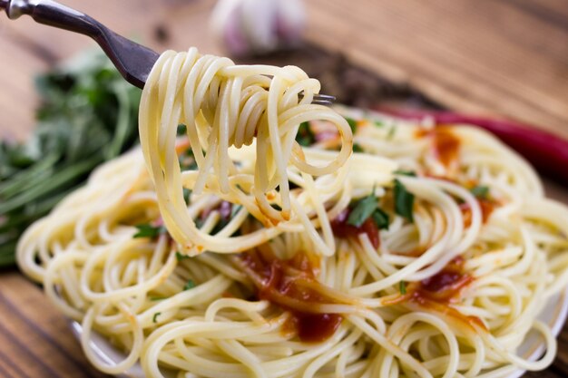 Op een vork pasta met ketchup, gekookte Italiaanse pasta op een vork close-up, maaltijd