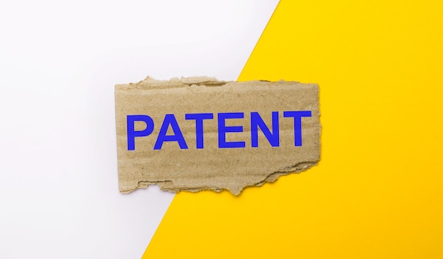 Op een witte en gele ondergrond bruin gescheurd karton met de tekst PATENT