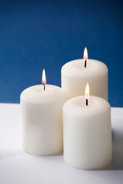 Op een witte tafel branden drie witte kaarsen.