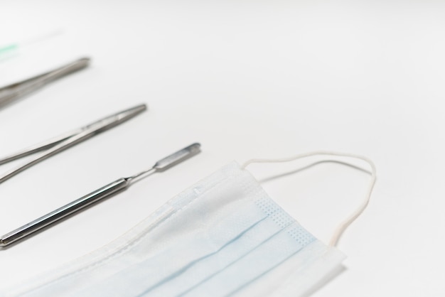 Op een witte tafel staan tandheelkundige instrumenten en een wit beschermend masker