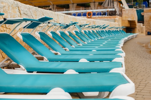Foto op een zonnige dag staan er veel nieuwe mooie blauwe ligstoelen bij het zwembad in het hotel. fijne vakantie vakantie. zomervakantie en toerisme.