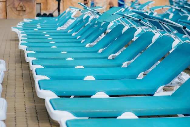Op een zonnige dag staan er veel nieuwe mooie blauwe ligstoelen bij het zwembad in het hotel. Fijne vakantie vakantie. Zomervakantie en toerisme.