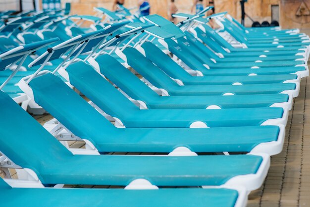 Op een zonnige dag staan er veel nieuwe mooie blauwe ligstoelen bij het zwembad in het hotel. Fijne vakantie vakantie. Zomervakantie en toerisme.