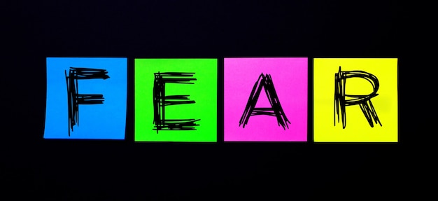 Foto op een zwarte achtergrond, felle veelkleurige stickers met het woord fear. illustratie