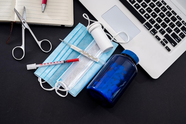 Op een zwarte achtergrond is een laptop notebook pen pillen spuiten maskers druppels butyl tabletten Geneeskunde concept