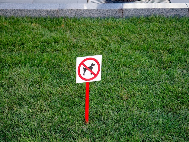 Op het groene grasveld staat een bord met het verbod op het uitlaten van de hond.