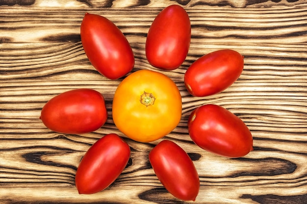 Op het houten oppervlak staan gele en rode tomaten.