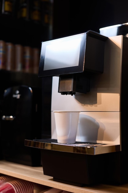 Op het koffiezetapparaat staat een papieren kopje koffie