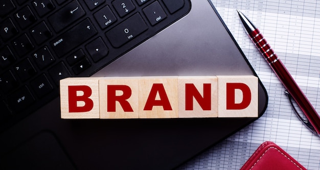 Op het toetsenbord staan naast een bordeauxrode balpen houten kubussen met het opschrift BRAND