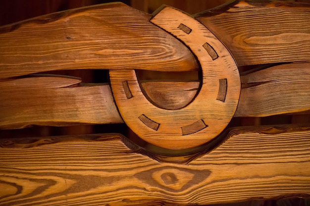 Op houten planken gesneden houten hoefijzer. Symbool van geluk. Textuur van een boom. Hoefijzer. Getextureerd bord