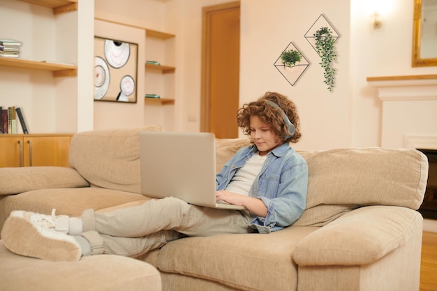 Op internet. Een jongen met krullend haar die tijd doorbrengt op internet en er betrokken uitziet