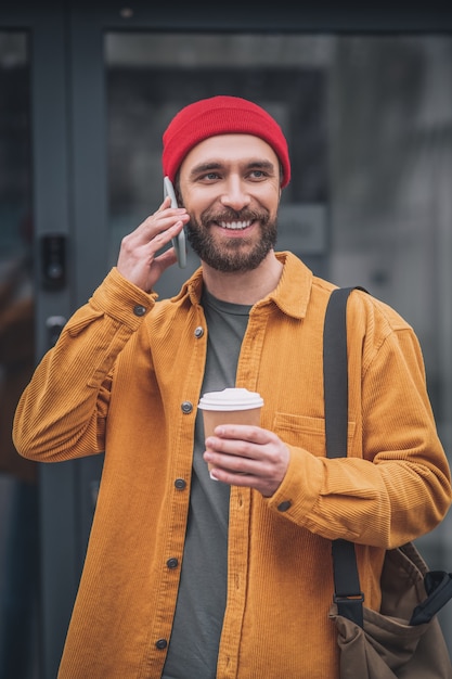 Op internet. Man in een oranje jasje met een telefoon in zijn handen