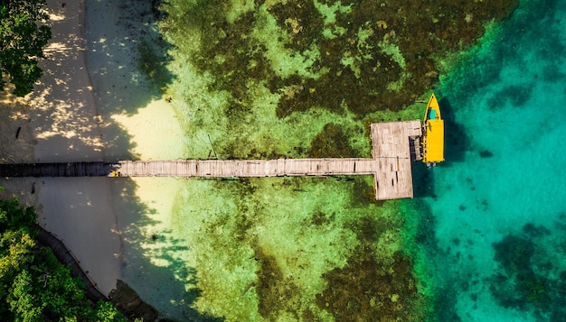 Op naar de volgende locatie Hoge hoekopname van een banca-boot aangemeerd aan het einde van een promenade voor een eiland in Raja Ampat