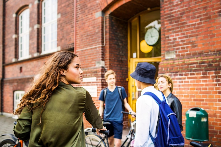 Foto op school lopen vier jonge meisjes samen buiten en knuffelen elkaar.