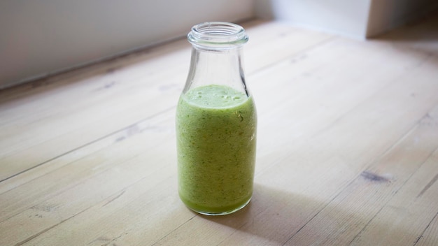 Op tafel staat een fles groene smoothie.