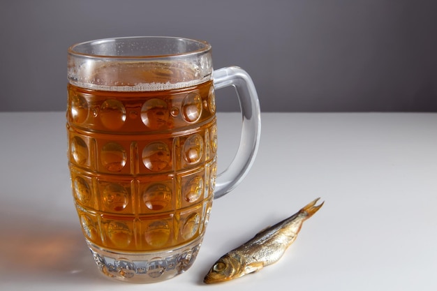 Op tafel staat een glas bier en gerookte vis.