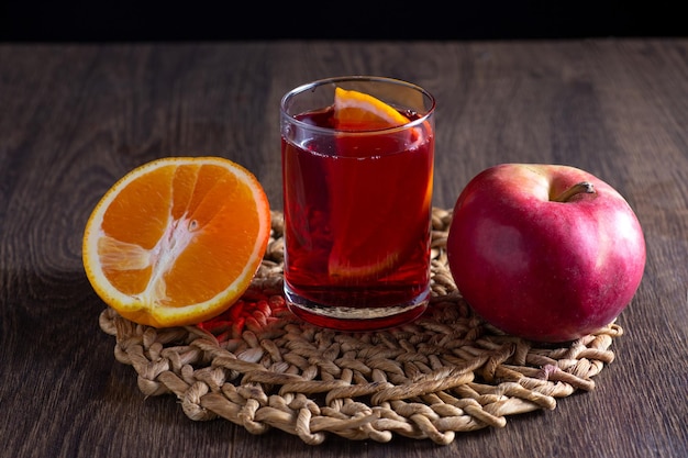 Op tafel staat sangria in een glas. Vlakbij ligt een appel en een sinaasappel.