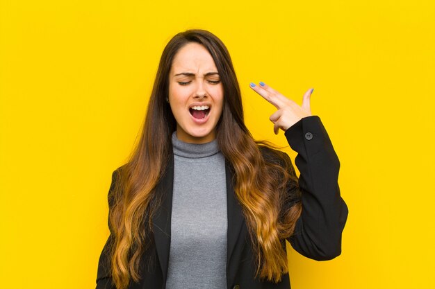 op zoek ongelukkig en gestrest, zelfmoord gebaar maken pistool teken met de hand, wijzend naar het hoofd