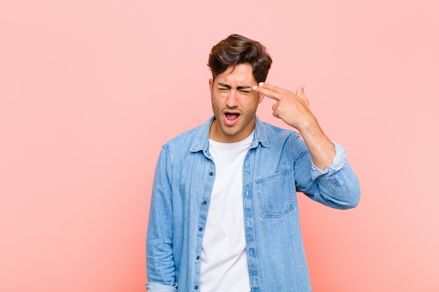 op zoek ongelukkig en gestrest, zelfmoord gebaar maken pistool teken met de hand, wijzend naar het hoofd