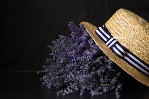 op zwart een groot geurig boeket van lavendel met een hoed en een strik.