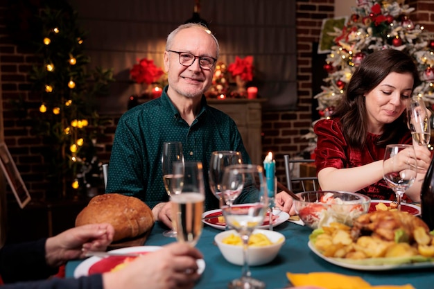 Opa aan de eettafel met de familie die een traditionele maaltijd eet en kerstvakantie thuis viert Oudere volwassenen die samenkomen bij een feestelijke bijeenkomst tijdens een seizoensgebonden evenement in de winter