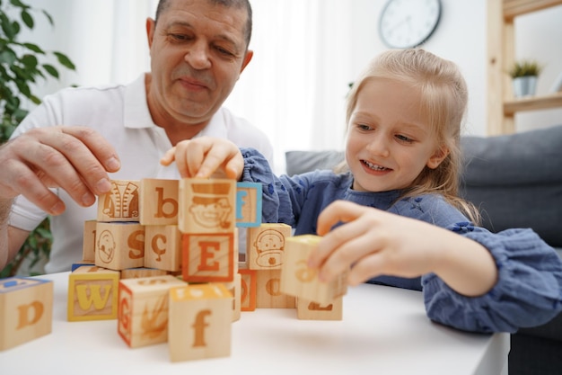 Opa en kleindochter spelen houten kubussen in de woonkamer