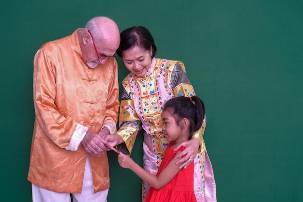 Opa en oma in hun traditionele Chinese kleding delen hun liefde met kleindochter tijdens het nieuwe maanjaar 2023