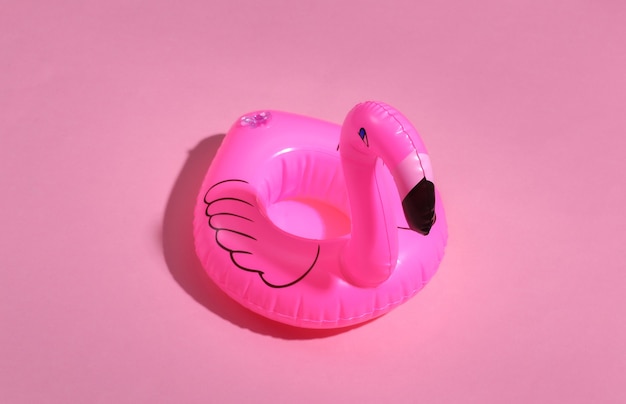 Opblaasbare roze flamingo op roze zonnige achtergrond. Zomer vakantie concept. minimalisme