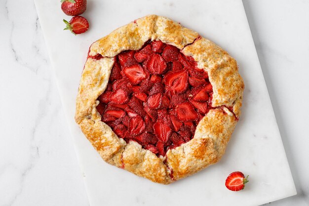 Open aardbeientaart op marmeren bord Aardbeiengalette Zelfgemaakte gebakken cake met aardbei Bovenaanzicht