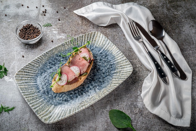 Open bacon and radish sandwich on a gray stone table