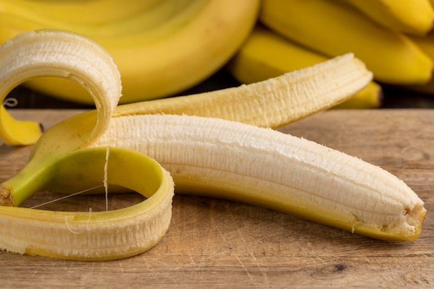 開いたバナナがテーブルの上にある木の板の上に熟した黄色のバナナ