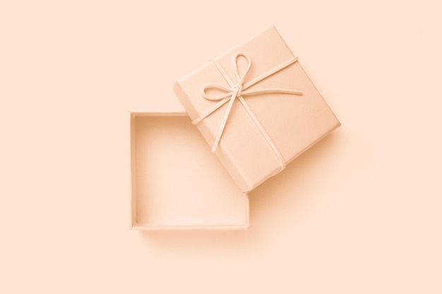 Open beige square gift box with a bow top view