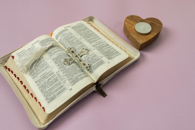 Open bible in Russian cross and candle holder in the shape of a heart