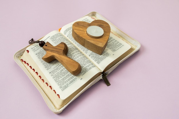 Open bijbel in Russisch houten kruis en kandelaar in de vorm van een hart