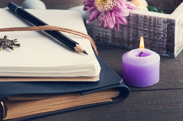 Open blank notebook, lit candle, flower