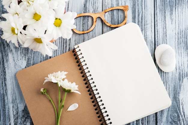 Open blank notebook, pebbles, flowers