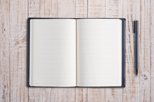 open blank notebook and pen on wood table