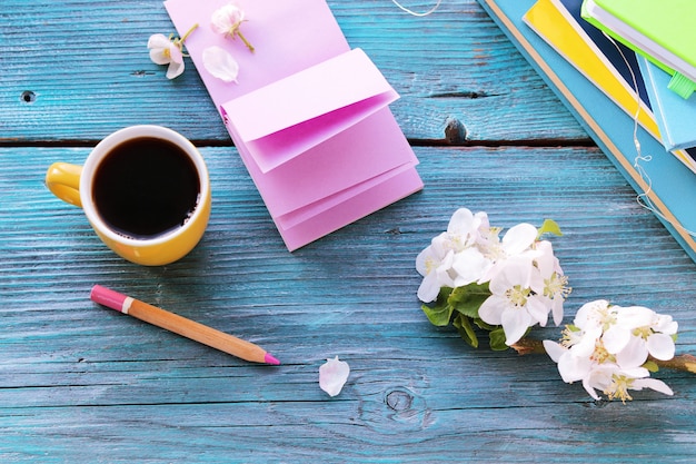 Open blank notebook and pencil, cup of coffee,  flowers on wooden table, spring