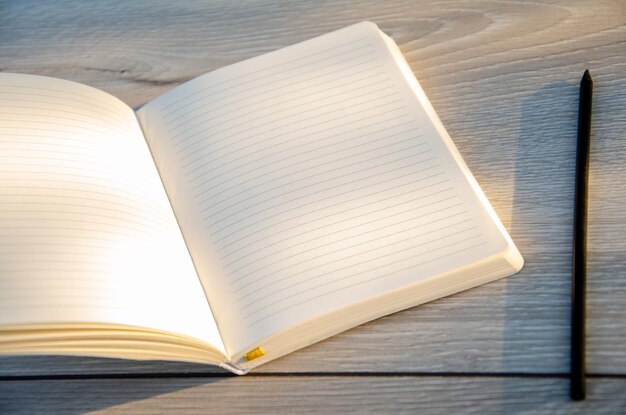 Photo open blank notebook with pencil and eraser on wooden table beautiful flowers in composition empty space for text