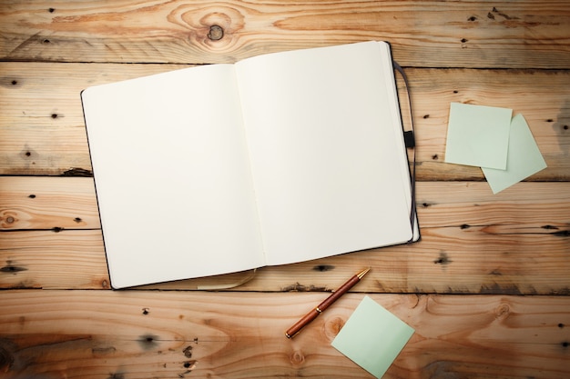 Open blank notepad with empty white pages  laying on a wooden table