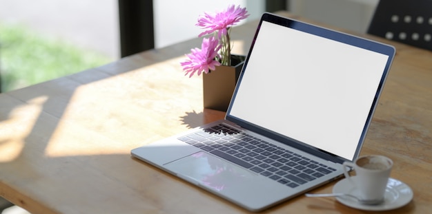 Open blank screen laptop computer in comfortable workspace next to the windows 