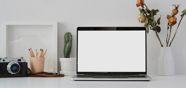 Open blank screen laptop computer in modern office room with office supplies