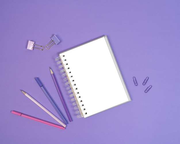 Open blank sketchbook liners and pencils on purple background Copy space Flat lay Mock up