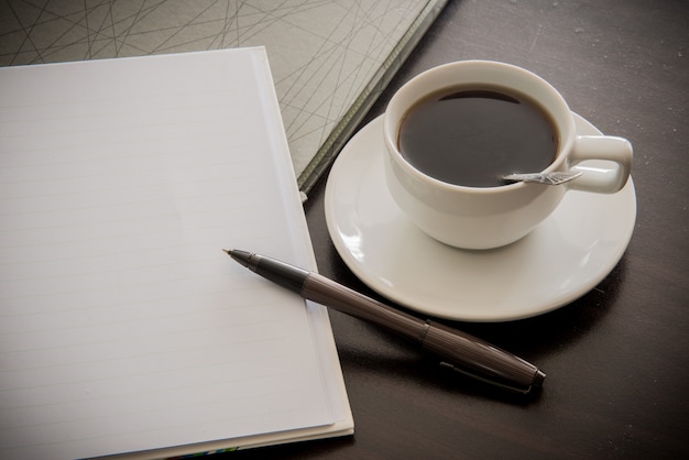 Open a blank white notebook, pen and cup of coffee