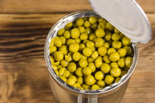 Open blikje groene erwten op houten tafel