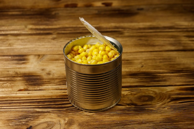 Open blikje maïs op houten tafel